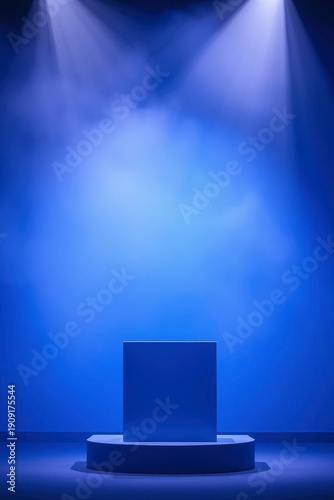 Blue stage lit by spotlights featuring a square block on a curved podium with smoke effects