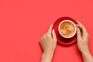 Female hands with cup of coffee on red background