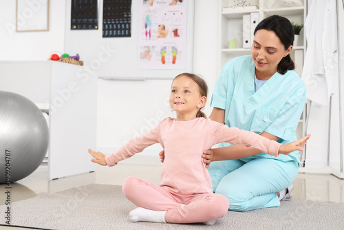 Female osteopath with little patient stretching and doing exercises in clinic