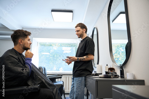 Man consulting client about desired hairstyle in barbershop