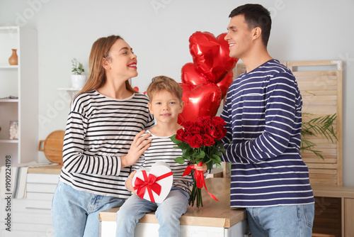 Little boy with gifts and his parents in kitchen on Valentine's Day