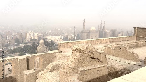 Elevated view of historic stone ruins overlooking the Cairo cityscape in Cairo, Egypt. Traditional architecture in the foreground with mosques and urban skyline in the Cairo.