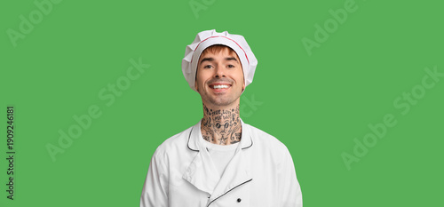 Smiling young chef on green...