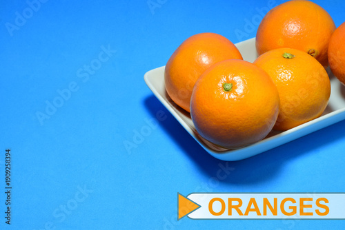 фотографія Natural oranges on a plate, blue background.