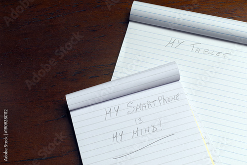 Symbolic photo about how phones replace traditional memory. Artistic metaphor of a smartphone representing the human mind written on layered notepads. With space for titles on the left.