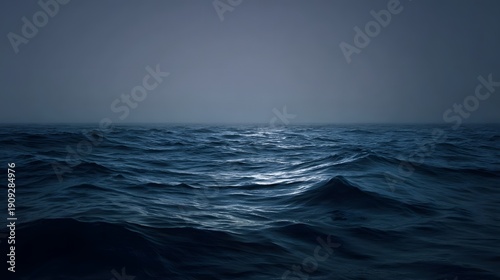 A vast dark choppy ocean under a hazy gray sky with subtle light reflections on the water surface