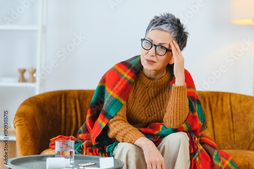Fotografi Senior woman suffering headache sitting on couch