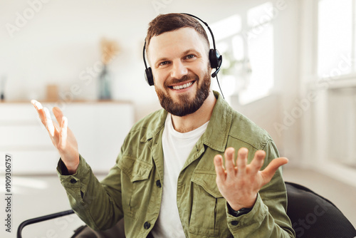 Fotografía Cheerful Male Freelancer Making Video Call Wearing Headset Smiling And Talking Looking At Camera Sitting In Chair At Home