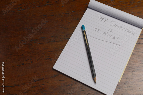 The Device Inside Me. Conceptual image showing notebooks with pencil text reflecting smartphone as extension of human brain. with copy space on the left for text.