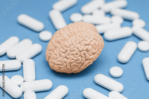 Принти на полотні Brain model with scattered white pills on blue surface