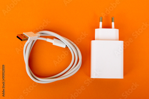 Various mobile phone chargers isolated on orange background.