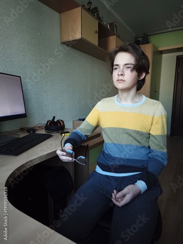 The teenager took off his glasses, Resting at Table. The teenager in a relaxed posture looking in front of him, Neurodiversity. Mental Health and Digital Balance