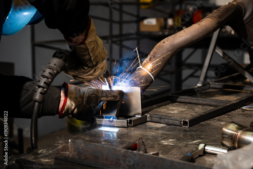Obraz na plátne Worker welds steel with shielded arc using flux-coated electrode