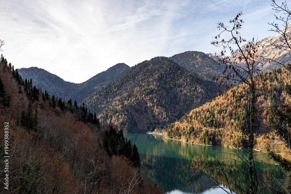 Fototapeta premium Majestic, serene mountain lake with a vibrant mixed evergreen and autumn forest backdrop, ideal for nature travel backgrounds and seasonal themes, showcasing pristine wilderness.