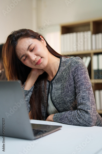 Fotografia Businesswoman experiencing discomfort and neck pain, rubbing her shoulder and cl