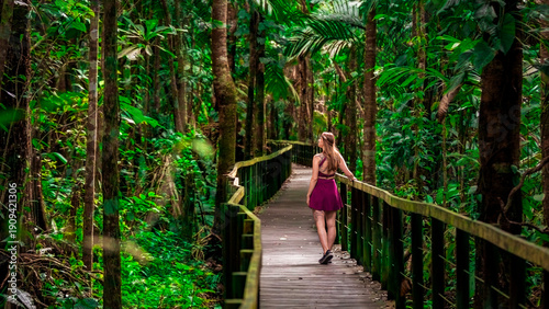 Pretty girl hikes on a wooden path through the tropical rain forest of Cahuita National Park in Costa Rica