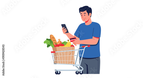 A modern man is confidently holding a credit card and checking his smartphone while standing beside a shopping cart overflowing with fresh groceries.