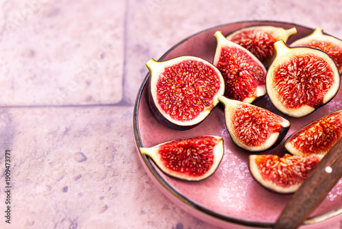 Close-up of bright, fresh, ripe figs on plate, pink stone background