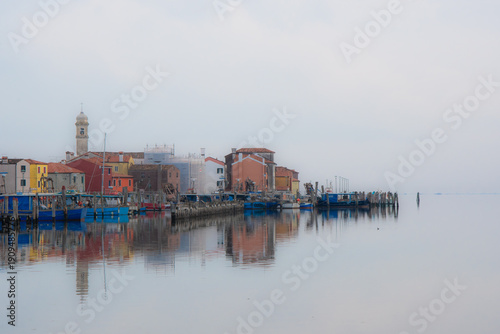 Panorama del borgo di Portosecco sull'isola di Pellestrina con le case che si riflettono nell'acqua in una giornata invernale di foschia