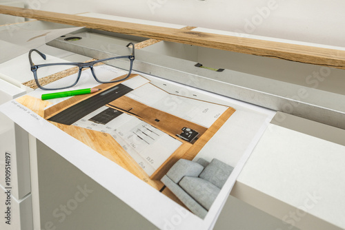 Designing new kitchen furniture, glasses, pencil, and ruler on a drawing board, designer designs built-in units,