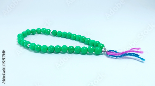 Islamic tasbih (string of prayer beads) made of green plastic material isolated on bright background.