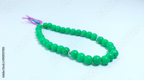Islamic tasbih (string of prayer beads) made of green plastic material isolated on bright background.