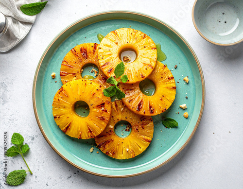 Roasted pineapple slices with tajin seasoning and honey drizzle on turquoise ceramic plate.