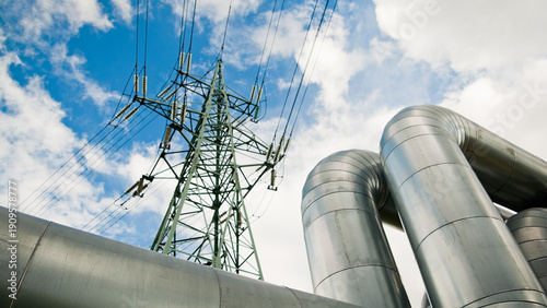 a pipeline and a power transmission tower against a blue sky and clouds