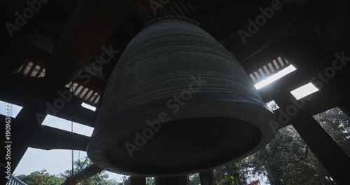 Silhouette beneath old, majestic, massive Japanese bell