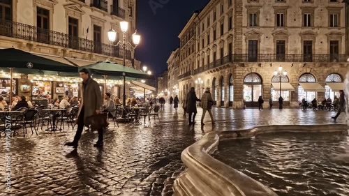 Evening stroll in vibrant city square. People enjoy atmosphere at outdoor café. Historic architecture lights up night. Relaxing ambiance fosters social interactions.