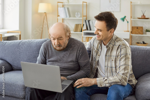 Slika na platnu Senior with laptop computer, grown-up son, adult grandson and old father learnin