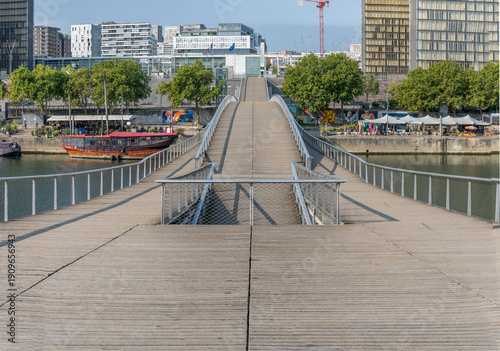 Paris, France - 08 15 2025: La Seine River. Panoramic view of the Simone de Beauvoir footbridge and the towers of the François-Mitterrand Library background