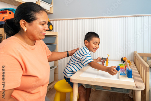 Mother teaches son at home with toys on a table