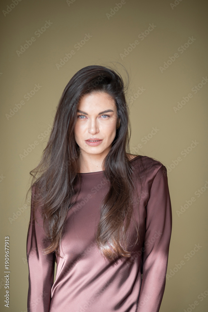 Obraz premium A beautiful brunette girl with a fresh orchid flower in a chocolate-colored dress