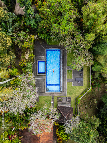 Woman jumping headlong into a pool surrounded by greenery