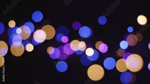 Soft, blurry, bokeh lights of blues, purples, and gold against a dark background