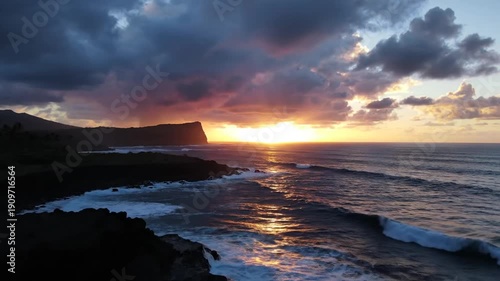 Dramatic sunset over a rugged coastline, with dark clouds and waves crashing on the shore