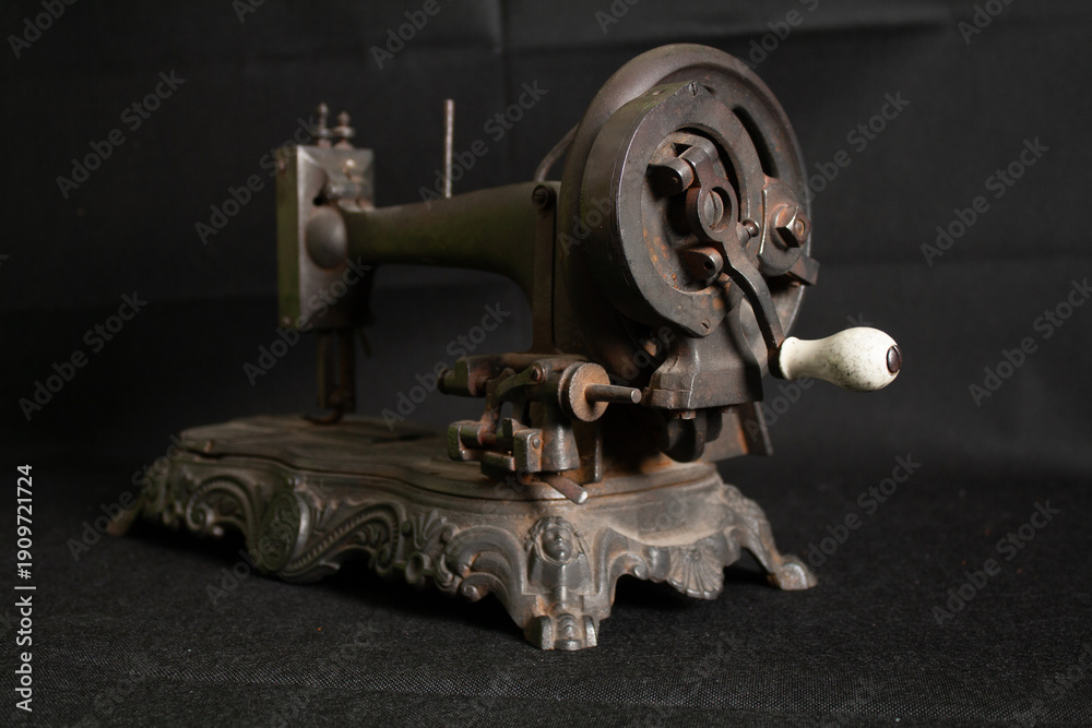 Fototapeta premium Close-up view of a very old, rusty sewing machine and its parts, showing corroded metal surfaces, worn mechanisms, and timeworn details. 