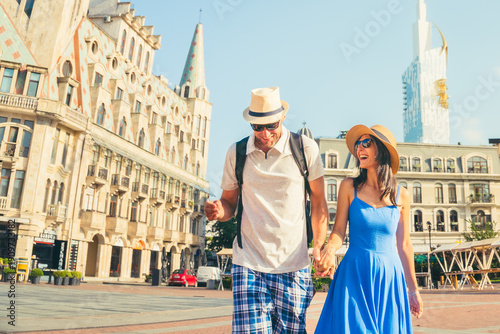 Happy young caucasian couple having fun walking in Europe square sightseeing Batumi city on holiday - Happy friends laughing together on vacation - People and summer holidays destination concept