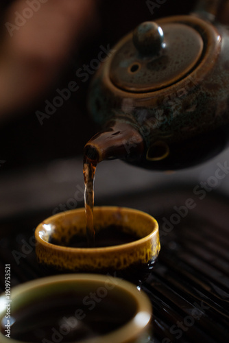 Pouring tea from teapot into small cup. Close up shot