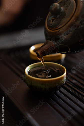 Chinese Tea Ceremony Close Up – Pouring Tea from Teapot into Small Cup on Tea Table