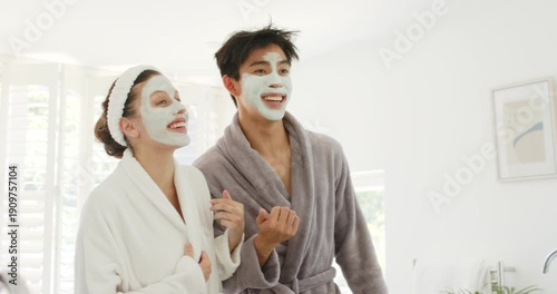 Diverse couple in twenties standing in bathroom wearing robes and masks, tracking offcamera cue