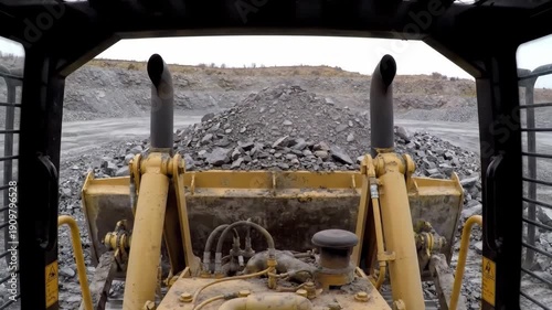 View from yellow skid steer loader cab working with rocks at the quarry.