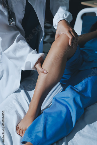 Doctor examining and supporting injured ankle of female patient in hospital room, providing medical assistance and treatment for sprain or fracture