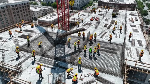 Construction workers build a large structure on a sunny day in the city with cranes and concrete
