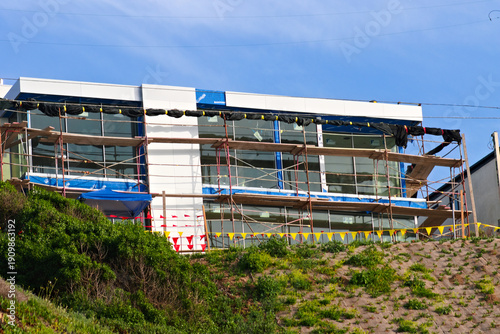 Modern building under construction in Torrance, California, with scaffolding and glass facade overlooking a coastal hillside.