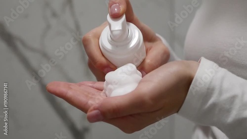 Skincare routine, female hands dispensing foaming face wash for hygiene.