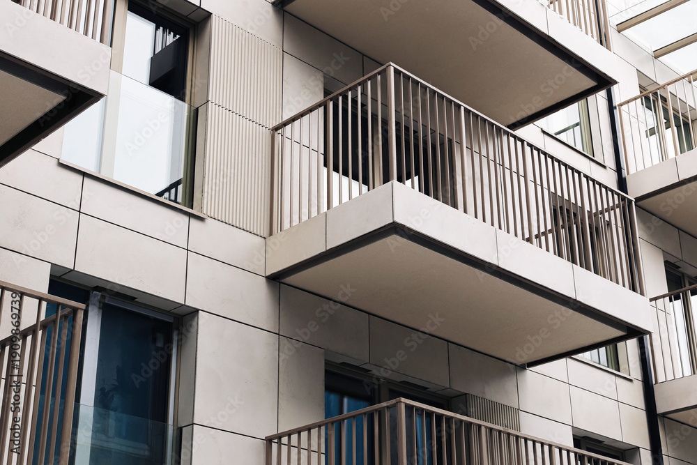 Fototapeta premium Modern apartment building balconies. White facade with metal railings. Residential block exterior detail. New housing building in city. Urban apartment architecture with repeating balcony structure.