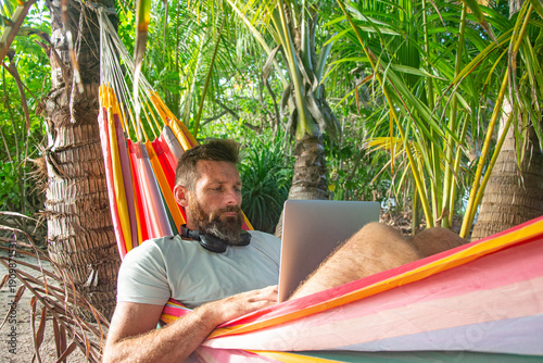 Digital Nomad Working on Laptop in Hammock on Tropical Beach