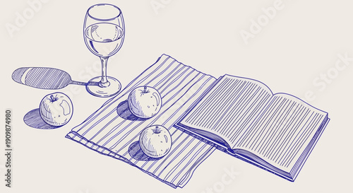 An open book lies on a striped cloth with fruit and a wine glass nearby, viewed from above.